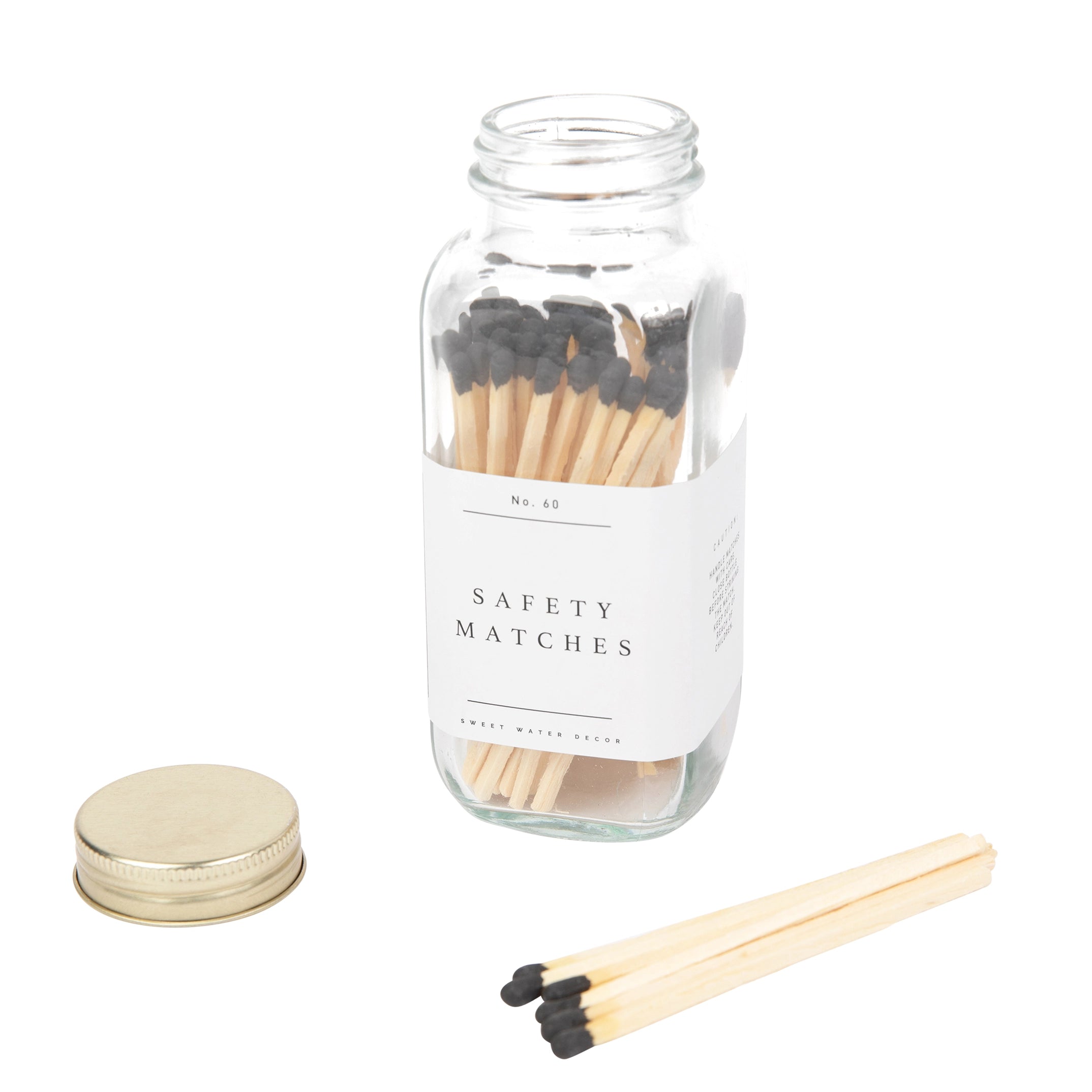 Glass jar with safety matches and a gold lid on a white background