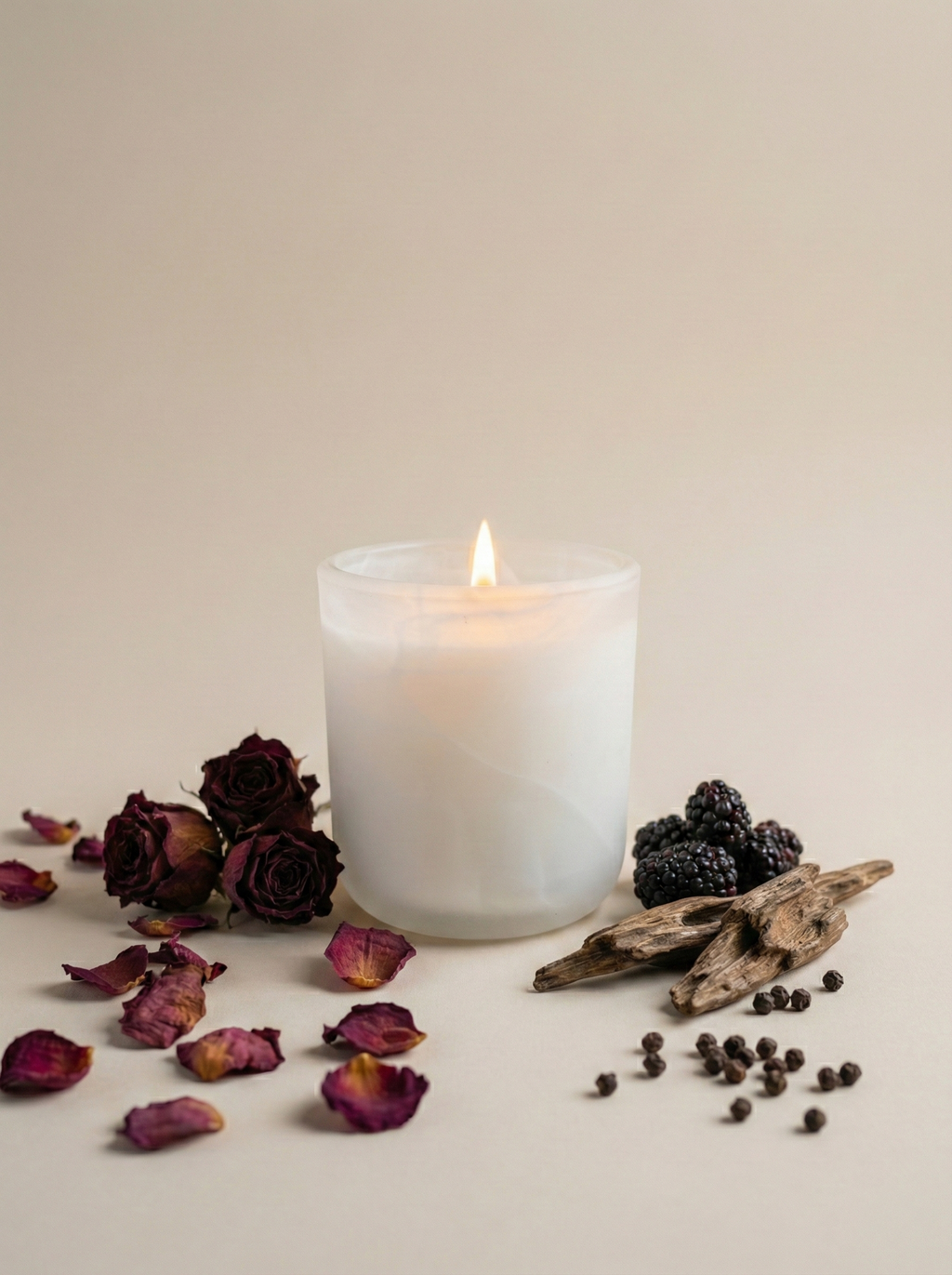 Candle with dried flowers and blackberries on a neutral background