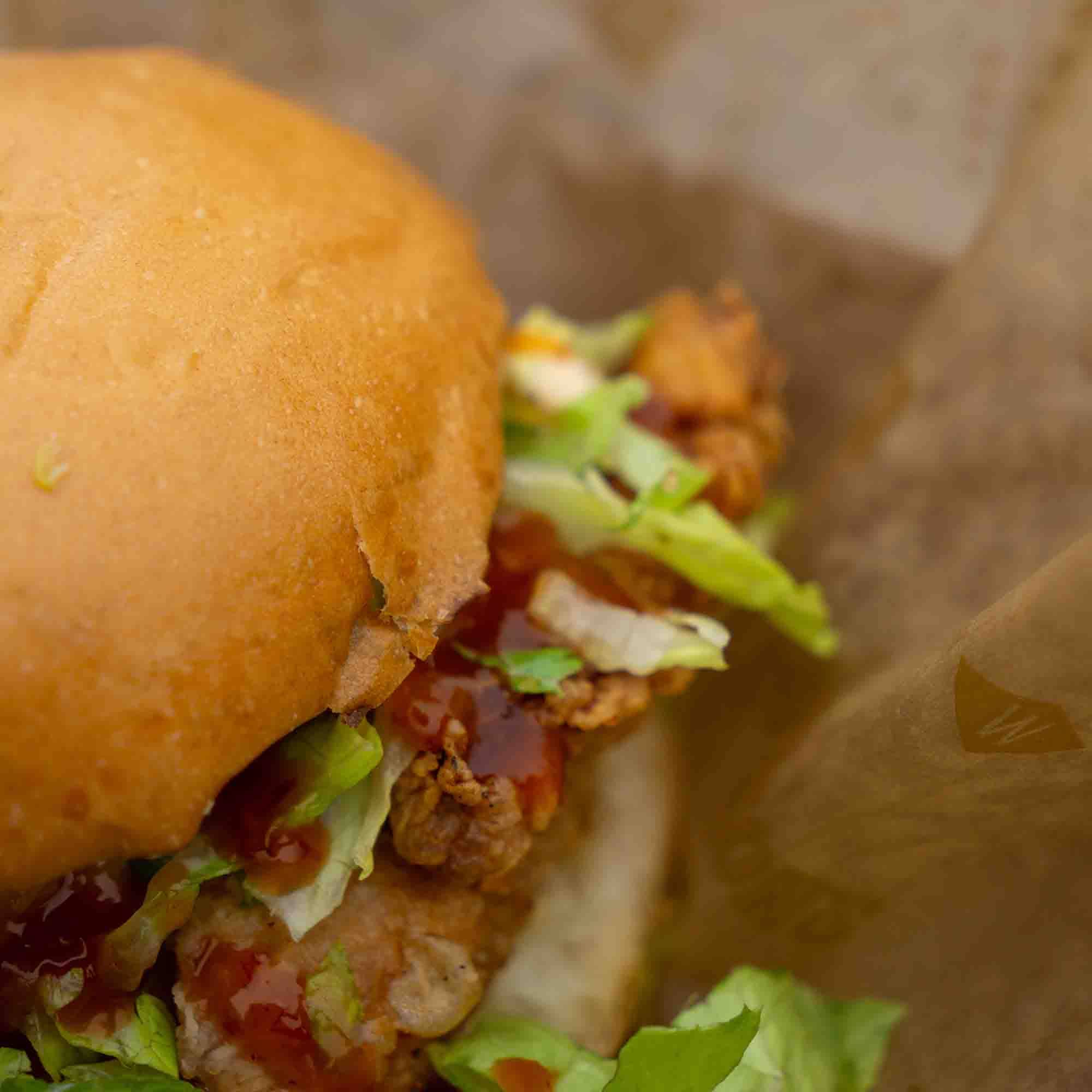 Close-up of a sandwich with lettuce and sauce on a brown paper background
